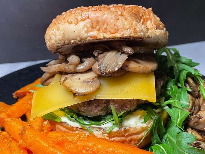 winterburger met oude kaas, rucola, paddestoelen en truffelmayonaise op een bord