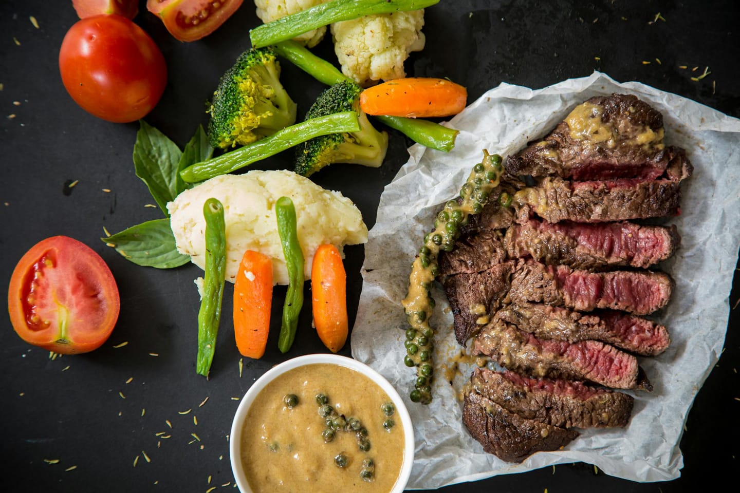 Een aangesneden gegrilde steak met pepersaus en gegilde groenten