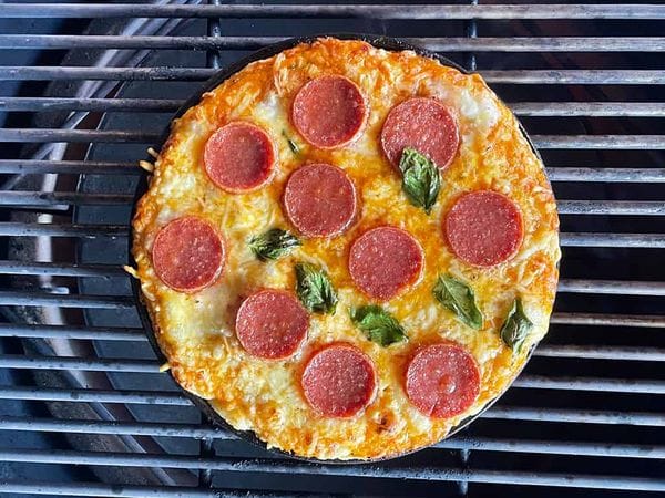 gebakken pan pizza in een skillet op het rooster van een barbecue