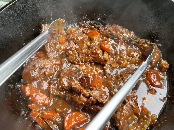 klaar gestoofd stoofvlees in een dutch oven met barbecuetang