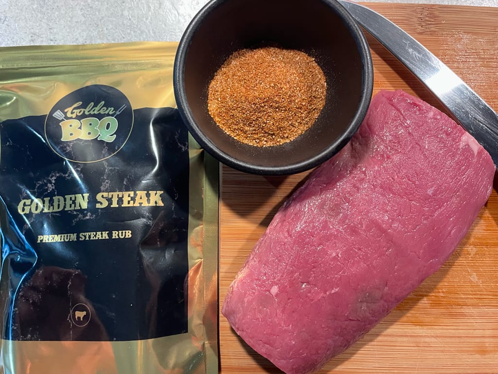 een zakje Golden Steak rub met daarnaast de rub in een bakje met een stuk diamanthaas er naast