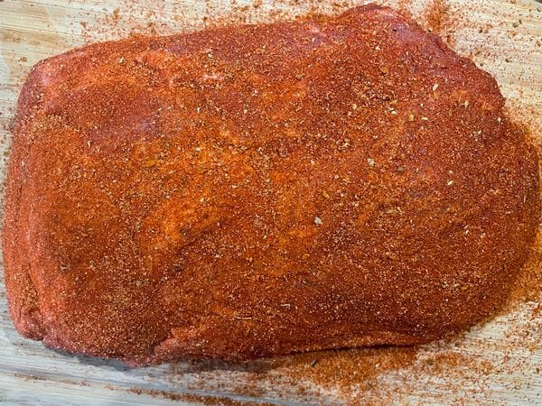 Een stuk procureur in barbecue rub, klaar om pulled pork van te maken